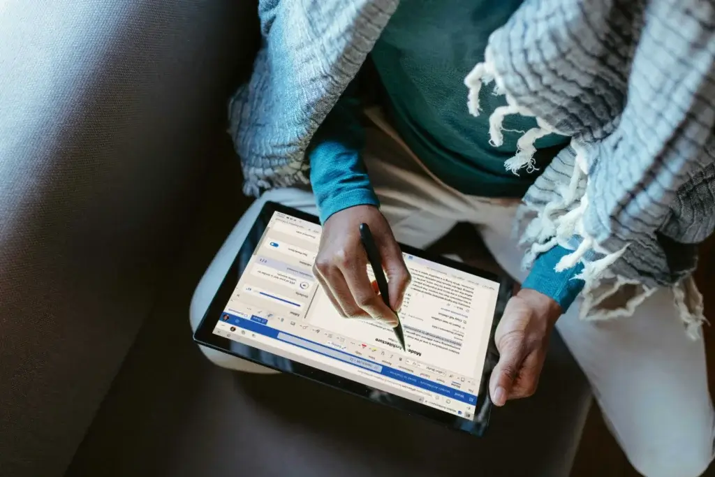 a man is working remotely on his tablet covered in a blanket