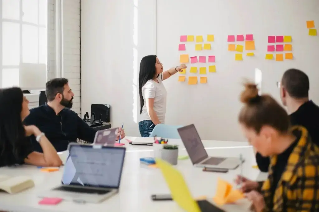 a woman is presenting tasks on a meeting to her colleagues in the office