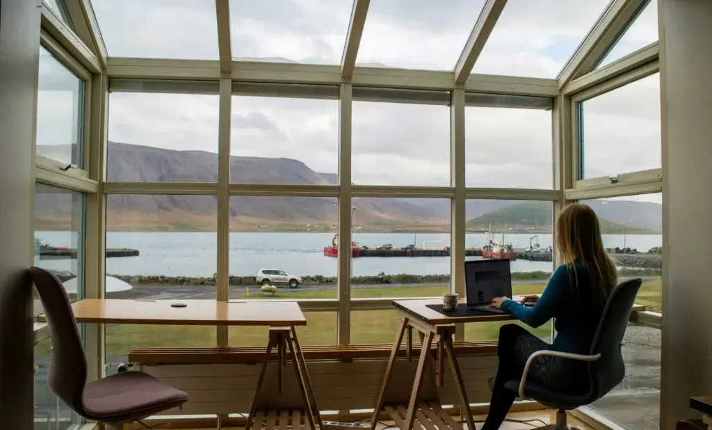 a woman is working on her laptop and watching in the window on a gorgeous nature