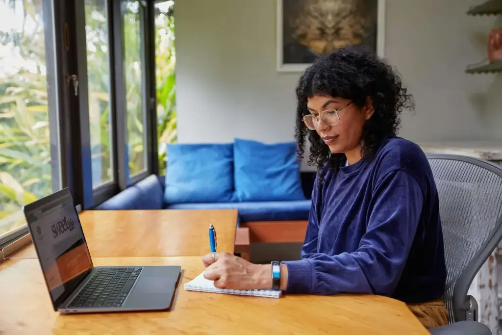 a woman who working remotely is taking the notes in her notebook