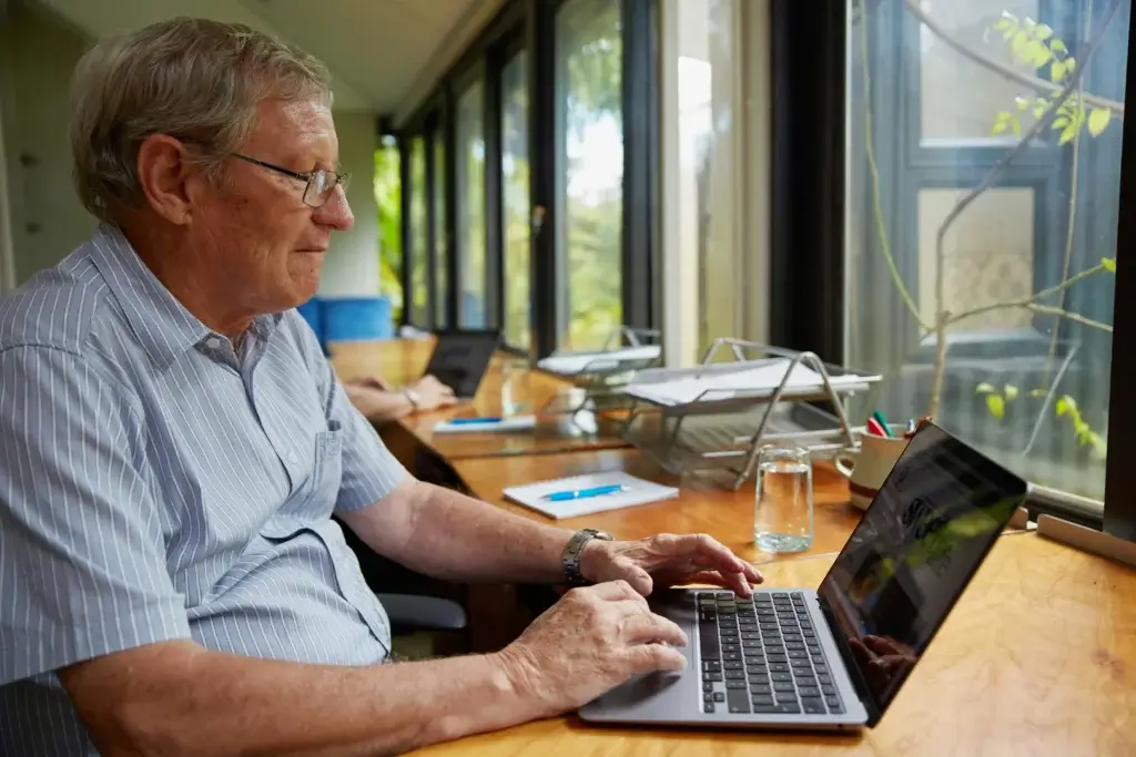 an old man is working on his laptop in the office