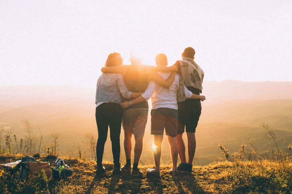 A group of four people is standing in front of the beautiful sunset.