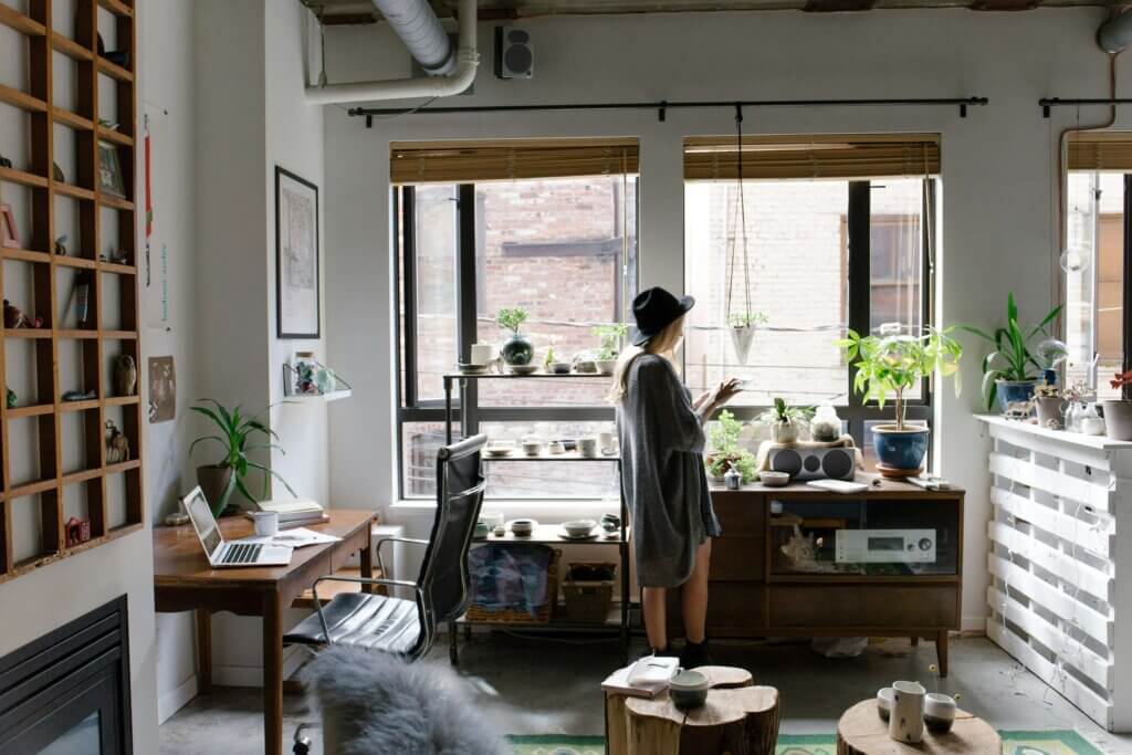 A woman in a cozy, plant-filled workspace practicing work-life balance statistics by tending to her indoor garden.