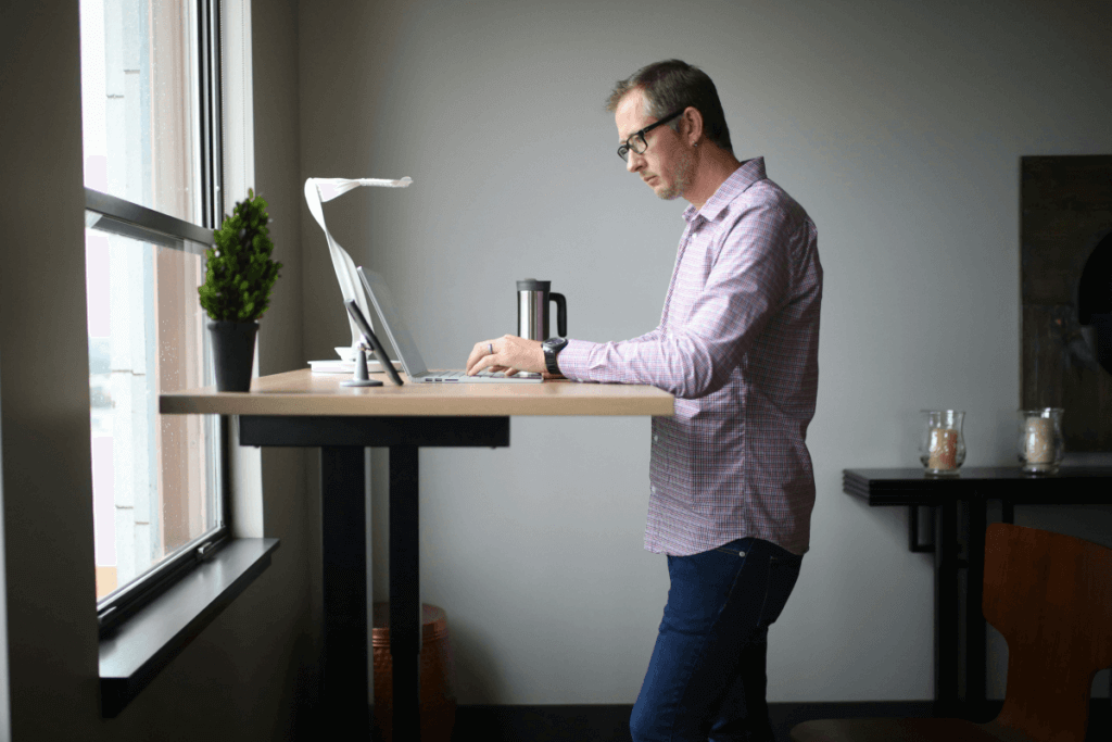 A man is working standing behind the Standing Office Desk