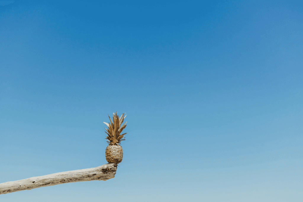 A golden pineapple balancing on a tree branch against a clear blue sky, symbolizing the benefits of work-life balance.