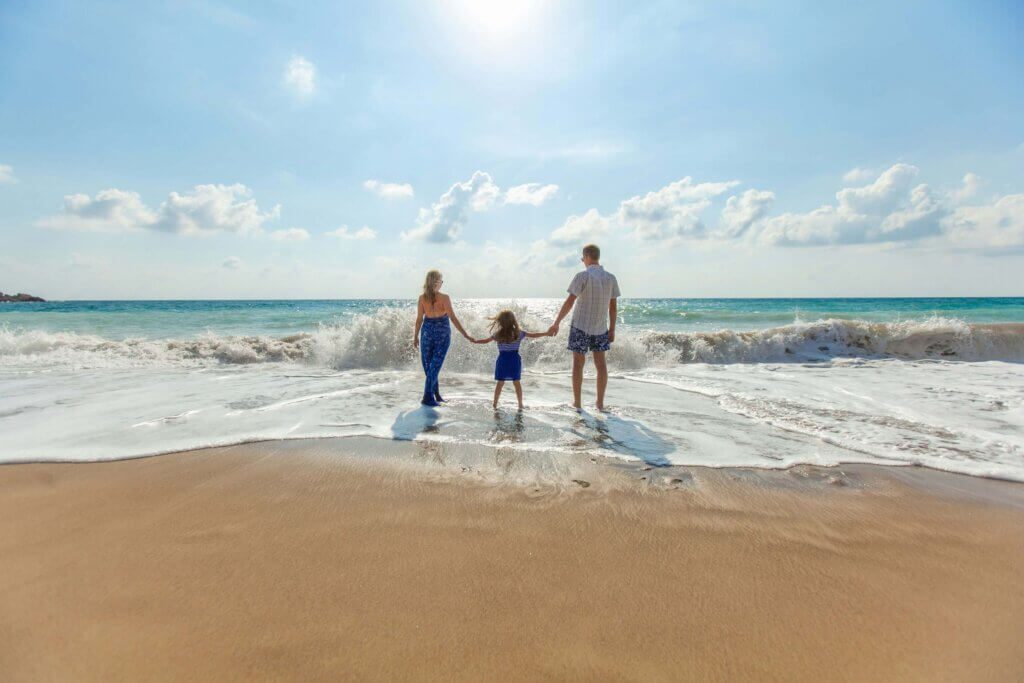 a family is standing on the beach holding each other's hands, which demonstrates balancing work and family life