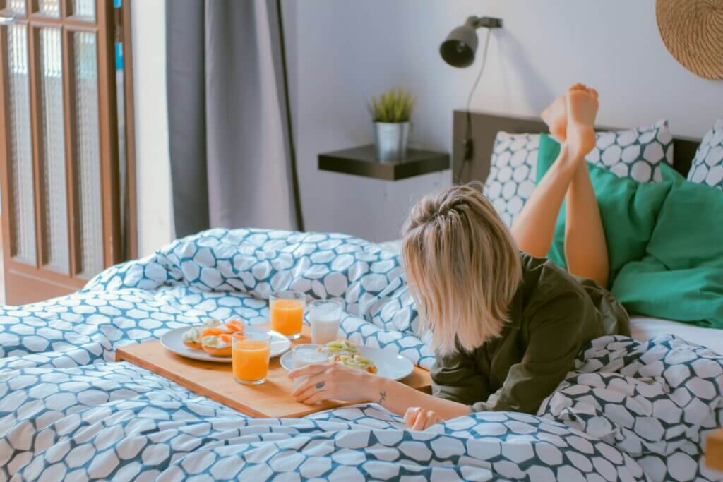 a woman enjoying her work-life balance career lying on a bed with a tasty breakfast