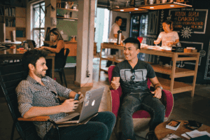 Two young professionals laughing and talking over coffee showing how to network with people in relaxed environments
