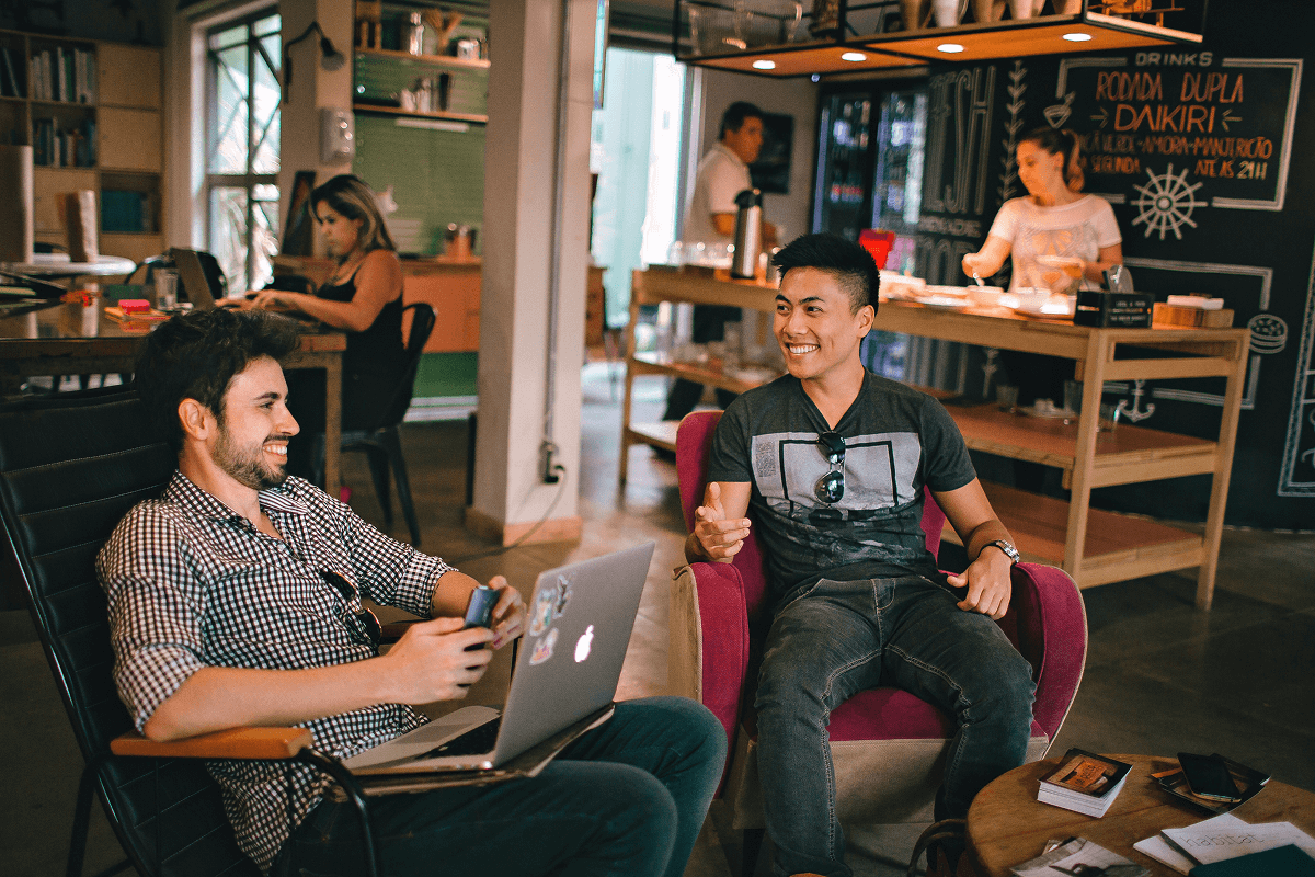 Two young professionals laughing and talking over coffee showing how to network with people in relaxed environments