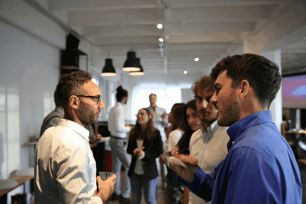 A group of professionals engaging in conversation at a modern office event, showcasing how to network with people in a social setting.
