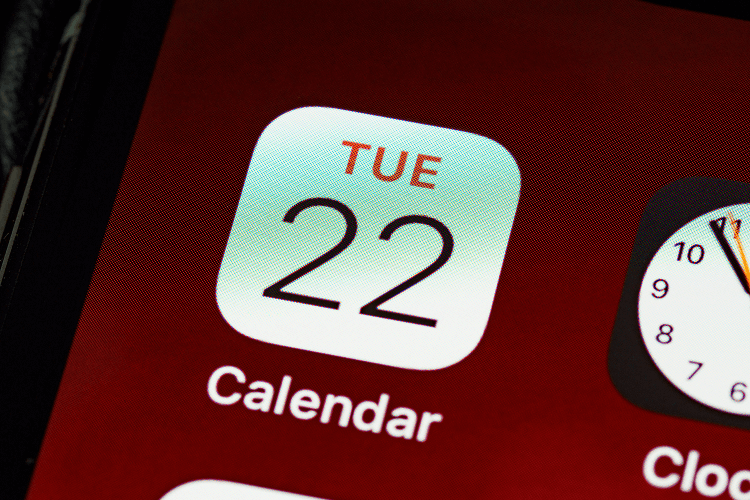 A smartphone screen displaying a calendar app icon with "TUE 22" and a clock app in the background, useful for tracking how many work days in a month on a digital device.