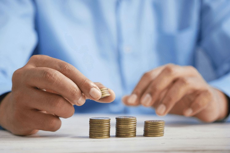 Hands stacking coins on a table, symbolizing financial planning in property management, a key skill for those learning how to become a property manager.