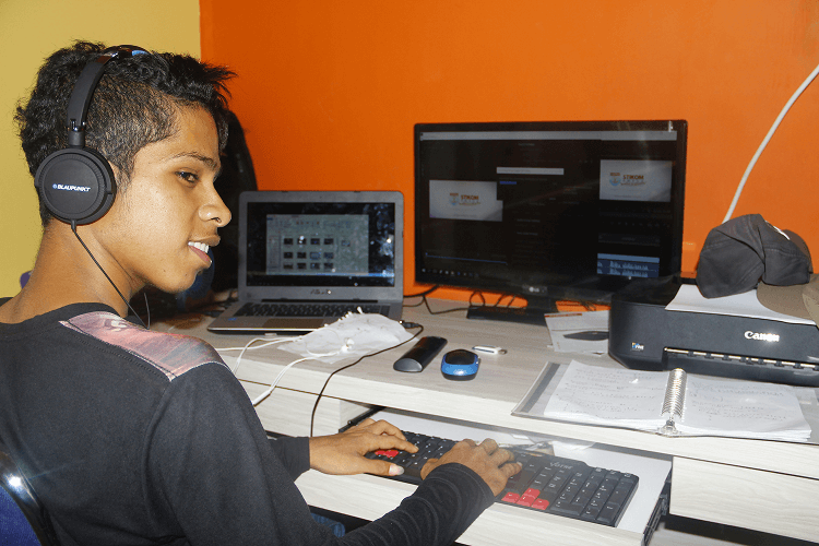 A teenage boy with headphones editing video on a dual-monitor setup, representing tech-savvy skills in a home office environment for what jobs hire at 13.